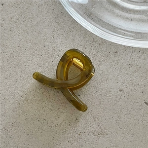 Macro view of olive green jelly resin hair claw clip with golden metal spring