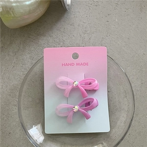 Détail de barrettes à nœud en dégradé rose avec strass sur une carte de présentation chic