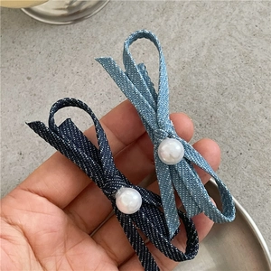 Detailed shot of denim bow hair clips with faux pearl accents in deep and light blue