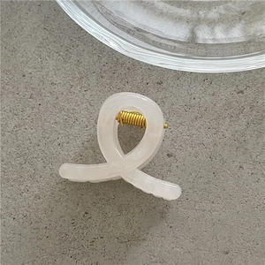 Close-up of a creamy white jelly hair claw clip with a durable gold metal spring