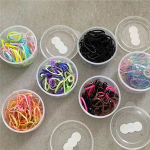 Dettaglio di sei set di elastici per capelli colorati in scatole di plastica trasparenti