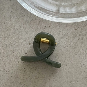 Macro view of dark green jelly texture mini hair claw clip with golden spring mechanism