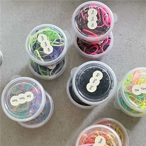 Dettaglio di elastici per capelli colorati in barattoli rotondi di plastica trasparente