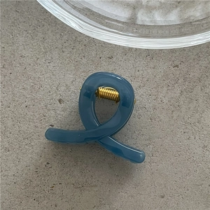 Detailed top view of Morandi blue resin hair claw clip with golden metal spring on stone