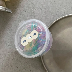 Dettaglio di elastici per capelli colorati per bambini in una scatola rotonda chiara