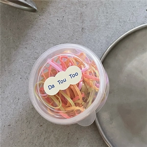 Dettaglio di elastici colorati per bambini in un contenitore rotondo trasparente