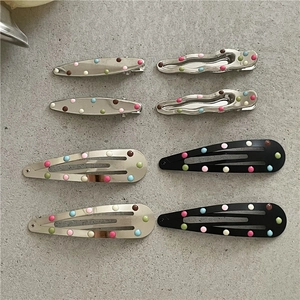 Dettaglio delle mollette per capelli a pois colorati su uno sfondo grigio minimalista