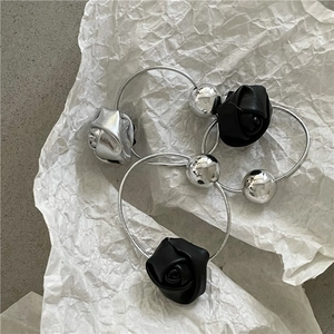 Close-up of silver metal spheres and rose petals on a textured white paper background