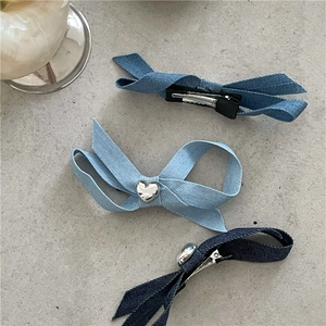 Détail de trois pinces à cheveux en tissu denim bleu avec petit motif cœur argenté