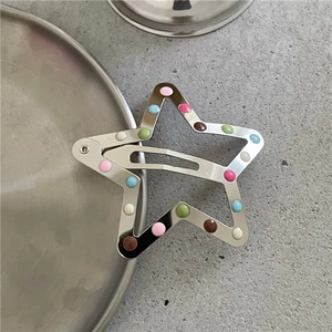 Dettaglio di un fermaglio per capelli a stella cava a pois colorati su vassoio
