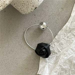 Detail view of silver metal bead and black resin rose on a modern minimalist ring