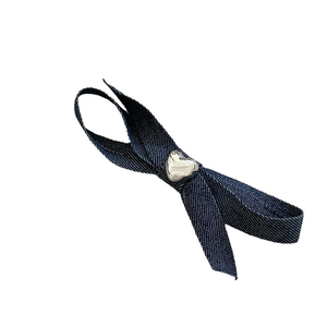 Barrette à cheveux nœud en denim bleu avec bouton cœur métallique sur fond blanc