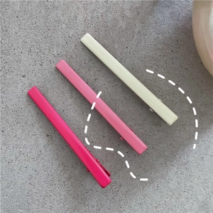 Vue macro détaillée de trois barrettes en métal mat rose et crème sur fond de pierre