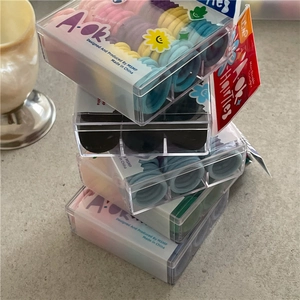 Close-up of baby-sized colorful elastic hair ties set in a clear square gift box