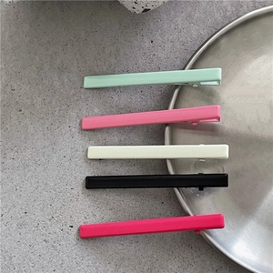 Détail de barrettes à cheveux colorées en métal en cinq teintes sur un plateau