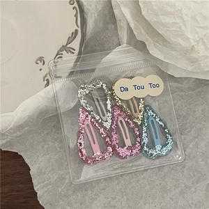 Détail de barrettes à cheveux en forme de cœur pailletées en cinq couleurs sur une assiette