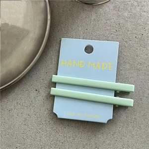 Vue détaillée de deux barrettes à cheveux rectangulaires vert clair en métal sur carte