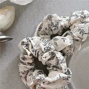 Off-white floral scrunchies with black branch patterns and delicate eyelet embroidery