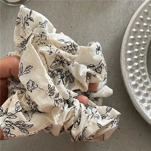 Handheld view of cream fabric floral scrunchie with delicate embroidery details
