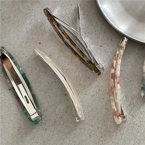 Detailed overhead view of acetate oval hair clips in four elegant marble and floral patterns