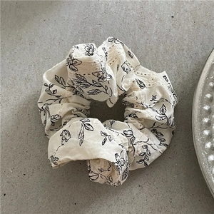 Detail of floral scrunchie in creamy white fabric with black flowers and lace trim