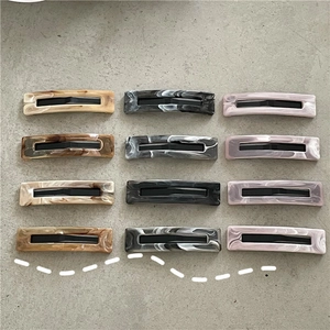 Flat lay of 12-piece rectangular marble acetate hair clips in brown, grey and purple
