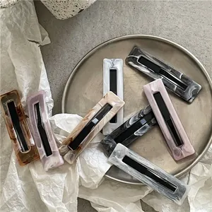 Rectangular marble texture hair clips in assorted colors on a minimalist metal tray