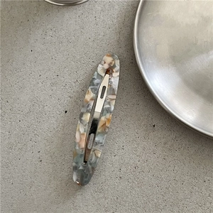 Detail view of acetate oval hair clip showing grey marble texture and smooth finish