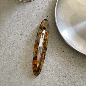 Close-up of tortoise shell acetate hair clip with blue highlights and silver metal clasp