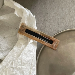 Detail of marble pattern hair clip with black accent on minimalist metallic tray