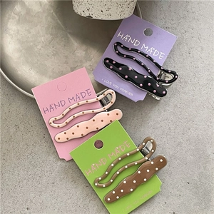 Detailed view of polka dot acrylic hair clips in wave and oval styles on a textured surface