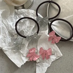 Glitter resin bow hair ties and clips in pink and silver on a decorative tray