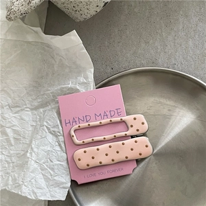 Detail of pink macaron hair clips with brown polka dots on a handmade display card