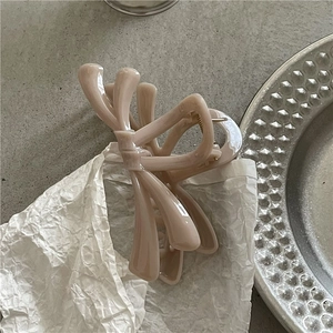 Close-up of translucent jelly-textured bow hair claw clip in soft nude pink finish