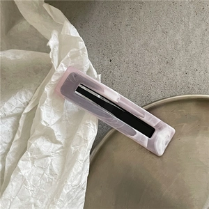 Macro shot of marble textured rectangular hair clip with cutout on a modern grey background
