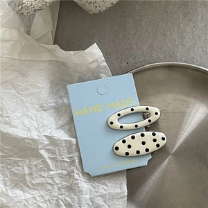 Close-up of cream-colored polka dot hair clips set on a decorative handmade card
