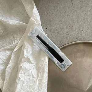 Macro view of marble texture hair clip with geometric cutout and rectangular acetate design