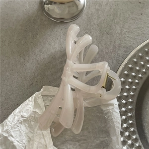 Detail of elegant creamy pearl bow hair claw clip on aesthetic textured background