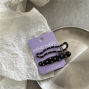 Close-up of sweet cream style alloy hair clips with pink polka dots on black finish
