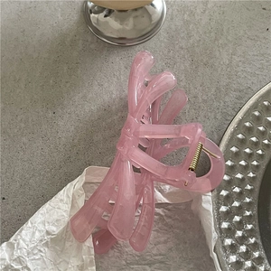 Detail of pink jelly bow hair claw clip with marble texture and gold metal spring