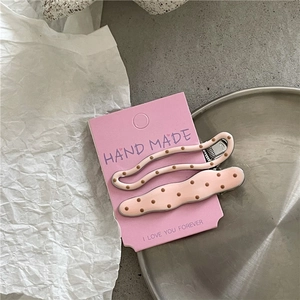 Detail of two pink polka dot cream style hair clips on a decorative display card