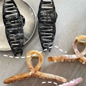 Dettaglio di fermacapelli effetto marmo con molla dorata e denti a presa forte