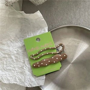 Detail of two brown hair clips with white polka dots on a green handmade display card