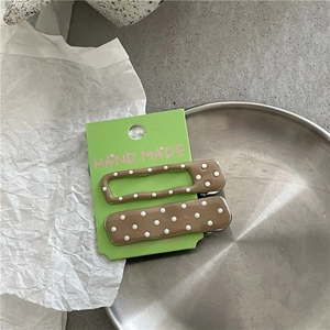 Close-up of brown polka dot alloy hair clips on handmade card in metal tray