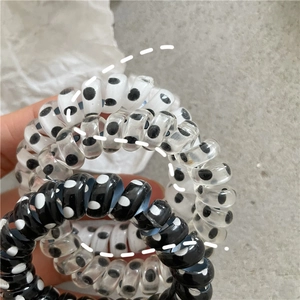 Close-up of three dotted spiral hair coils in black and white worn on a wrist