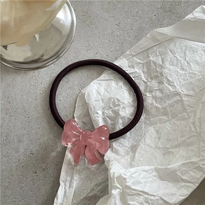 Detailed macro view of a translucent pink resin bow attached to a purple elastic hair tie