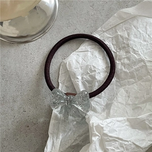 Close-up of a Korean style hair tie with a textured acrylic bow on a high-elastic brown band
