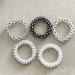 Five-piece set of spiral phone cord hair ties featuring black and white polka dot patterns