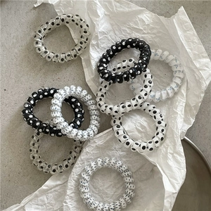 Detailed view of polka dot spiral hair ties in black and white on a textured surface