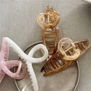 Eleganti mollette per capelli in marmo rosa, bianco e ambra su un vassoio di metallo
